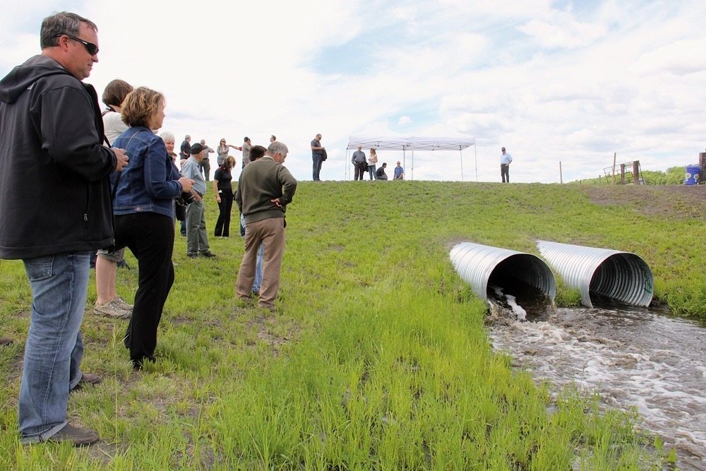 Municipal and conservation officials and local residents gathered at the Pelly’s Lake dam last week to see the gates open and the first of what will now be an annual early-summer release of water from the project.