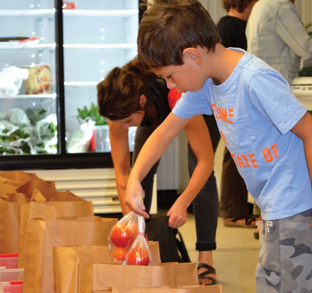 Kal-El Gobeil gives his mom a helping hand to packing and organizing the fresh produce.
