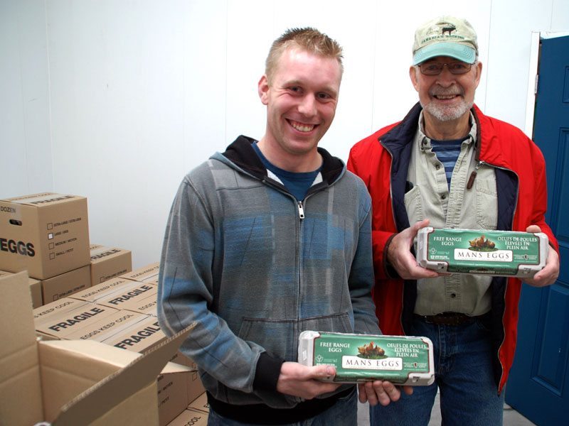 Two Men holding cartons of eggs.