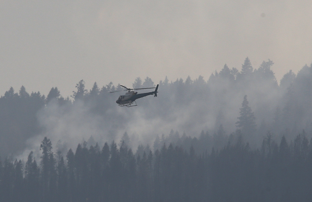 A helicopter flies over a wildfire south west of the town of Cache Creek, British Columbia, Canada July 18, 2017. Residents of the town were forced to evacuate 11 days ago and can now return to their homes. REUTERS/Ben Nelms - RC12041183D0