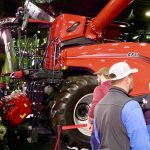 Case IH combine at a farm show with a farmer in the foreground.