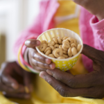 child's hands hold a cup of Cheerios cereal.