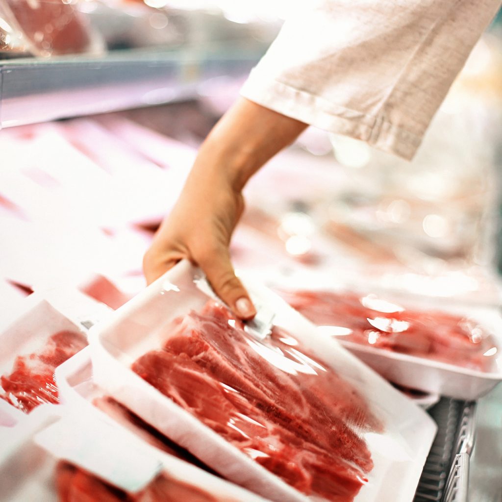 Closeup side view of unrecognizable woman choosing some fresh meat at local supermarket.