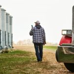 Farmer walks beside grain bins.