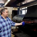 a man cooking beef brisket on a barbecue in a restaurant in Beijing, China