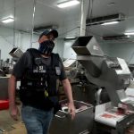 An agent passes meat being prepared during a raid by U.S. Immigration and Customs Enforcement (ICE) at a Glenn Valley Foods meat production plant in Omaha, Nebraska, U.S. June 10, 2025 in a still image from video.