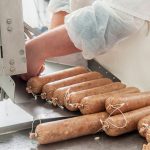 Close-up of a worker making sausage in a processing plant.