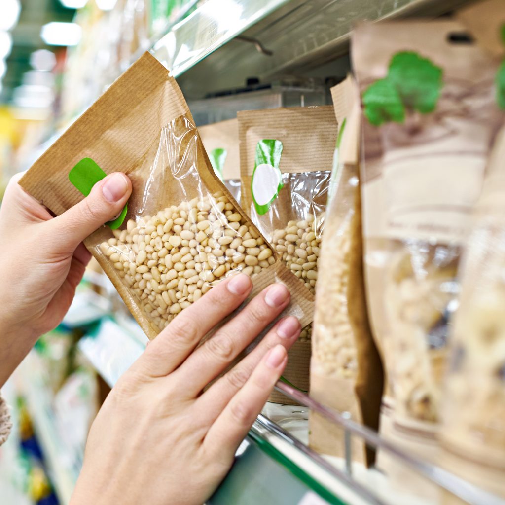 Hands take a package of food off a grocery store shelf.