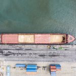 Overhead shot of a grain cargo ship at a pier.