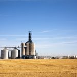 Grain elevator in the background with a harvested field and blue sky.