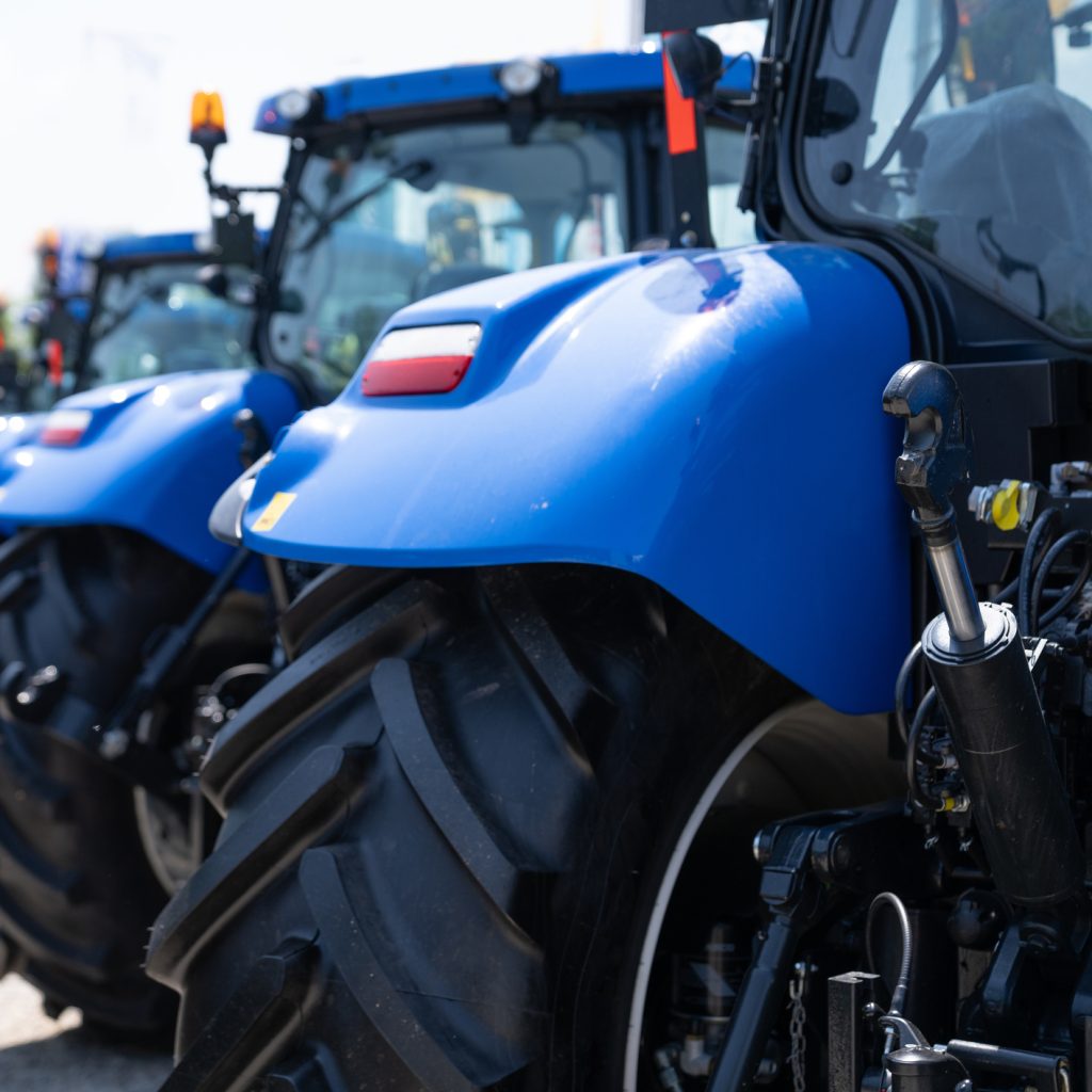 Close up of the fender and back wheel of a blue tractor in a row of tractors.