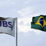 A JBS flag and Brazil flag fly side by side with the sky as background. Photo: REUTERS/Amanda Perobelli