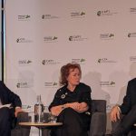 Arlene Dickinson sits between two people on stage while speaking in a panel discussion.