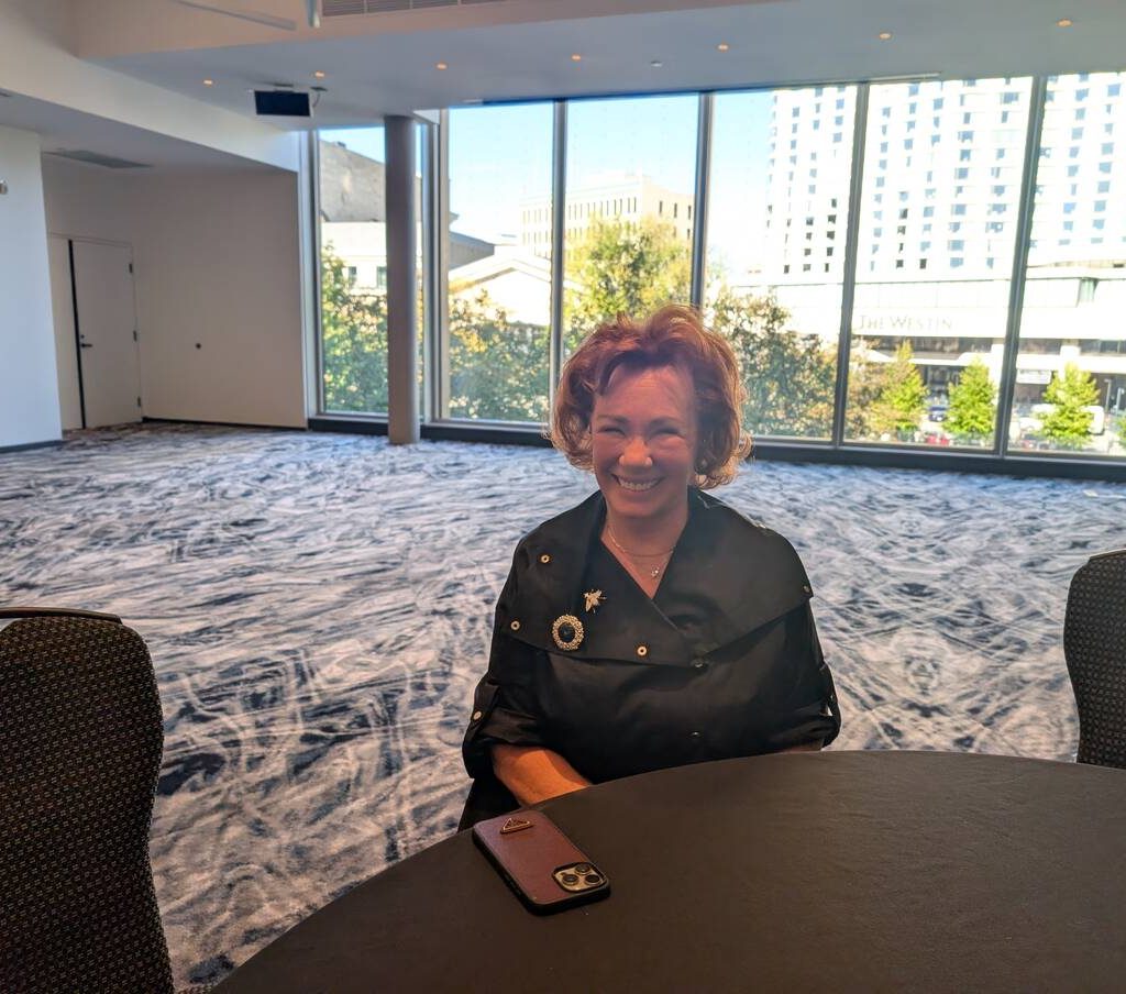 Arlene Dickinson sits at a table in a meeting room.