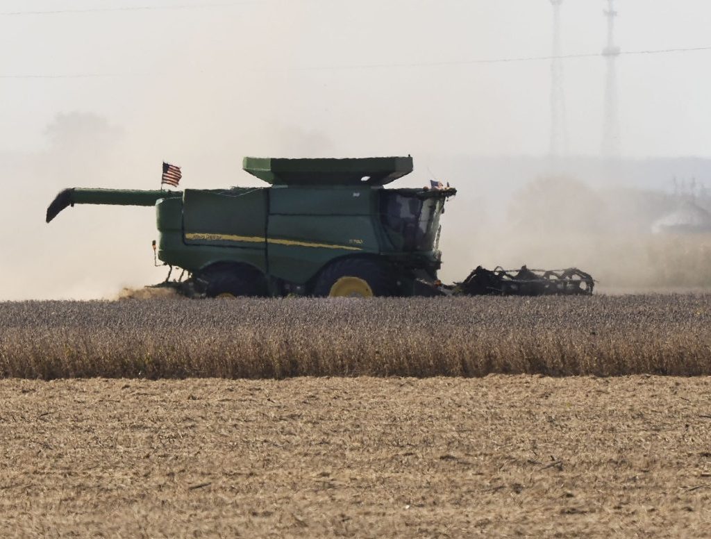 Heat waves are seen on an unusually warm September day as a farmer unloads his combine hopper into a waiting wagon as he harvests a soybean field in western Iowa in rural Woodbury County, Monday, September 29, 2025.