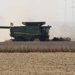 Heat waves are seen on an unusually warm September day as a farmer unloads his combine hopper into a waiting wagon as he harvests a soybean field in western Iowa in rural Woodbury County, Monday, September 29, 2025.