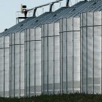 A row of six large grain bins at a grain terminal.