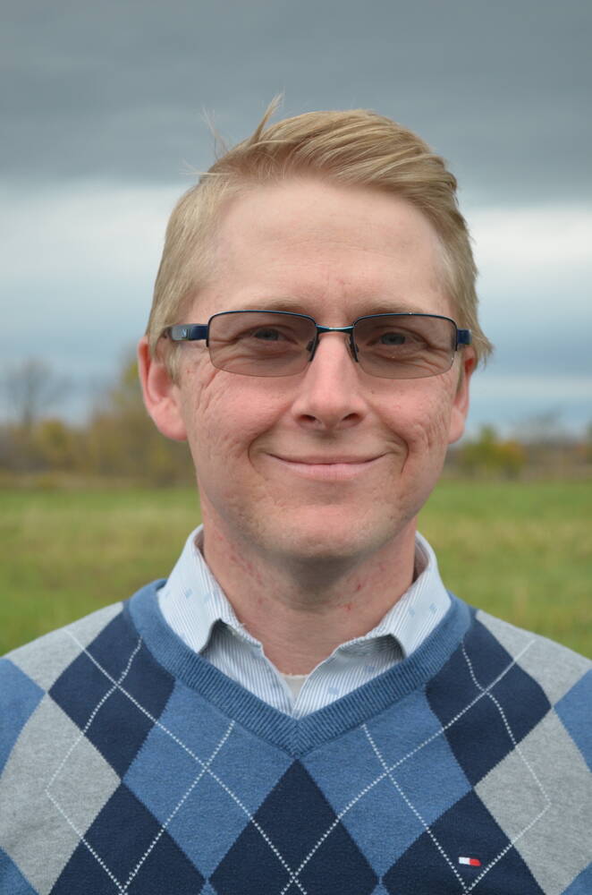 A close-up portrait of Tyler McCann. Tyler is blond and wears dark-rimmed glasses.