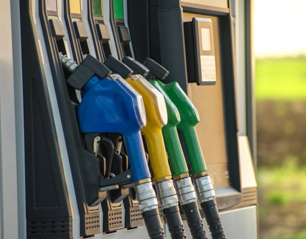 Fuel guns at the fuel station and green field in the background. Photo: Getty Images Plus.