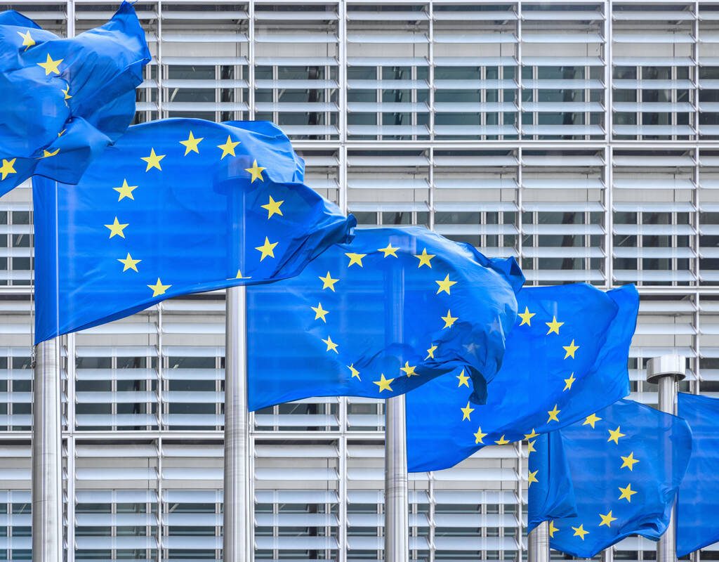 European Union Flags in a row in front of the facade of the European Commission Headquarter blowing in Brussels, Belgium.