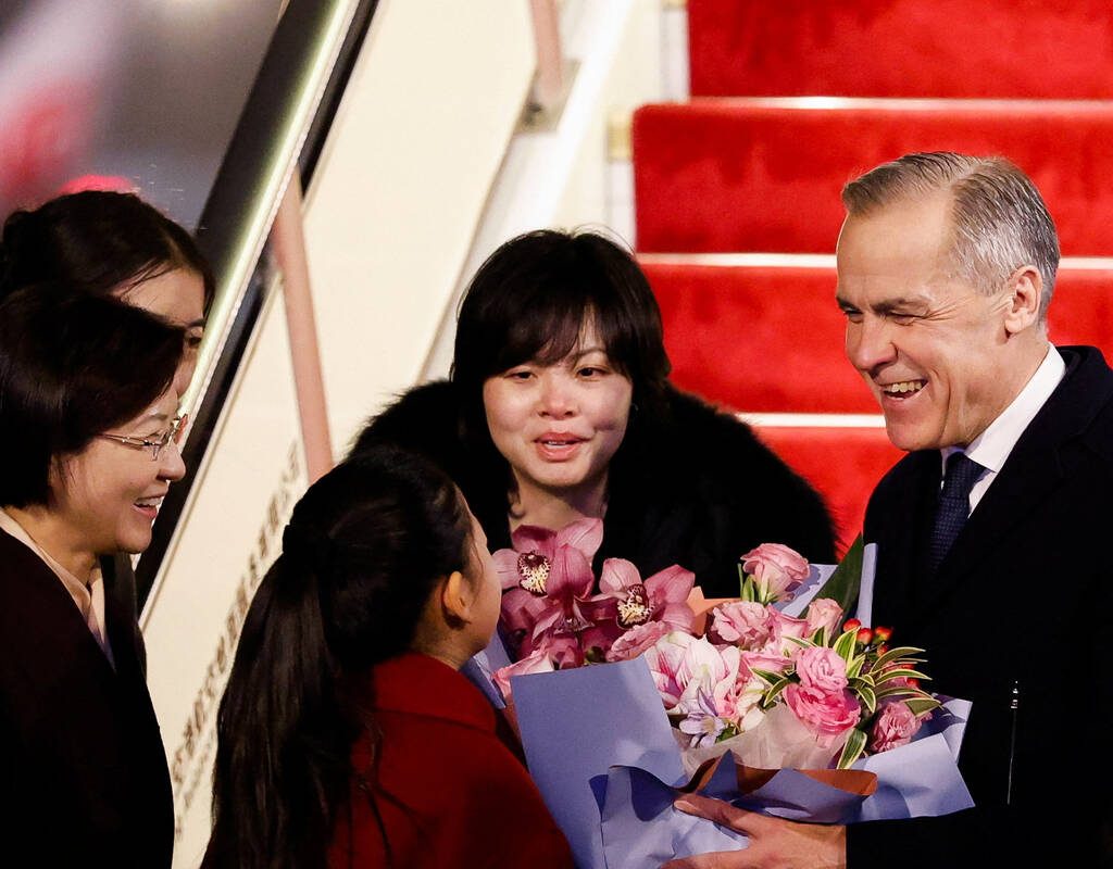 Canada's Prime Minister Mark Carney receives flowers from Lu You Ci, 11, upon his arrival at Beijing Capital International Airport, during the first visit by a Canadian Prime Minister to China since 2017, in Beijing, China January 14, 2026.