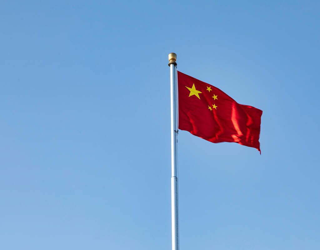 The flag of China flying against a blue sky.