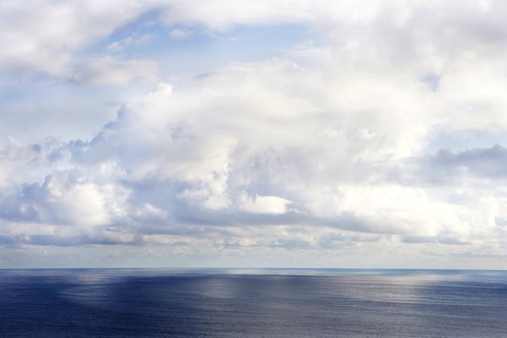 A calm Pacific ocean below a sky with puffy clouds. PHOTO: THINKSTOCK