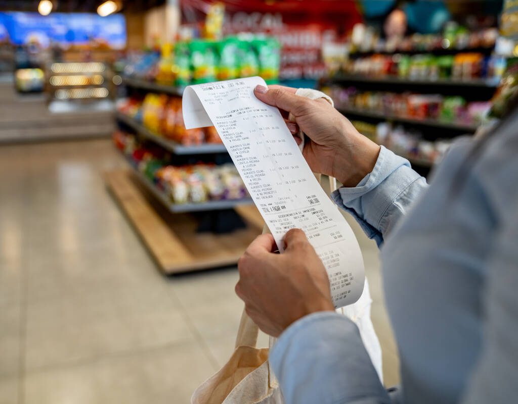 A person checks a receipt at a grocery store. Photo: Hispanolistic/IStock/Getty Images
