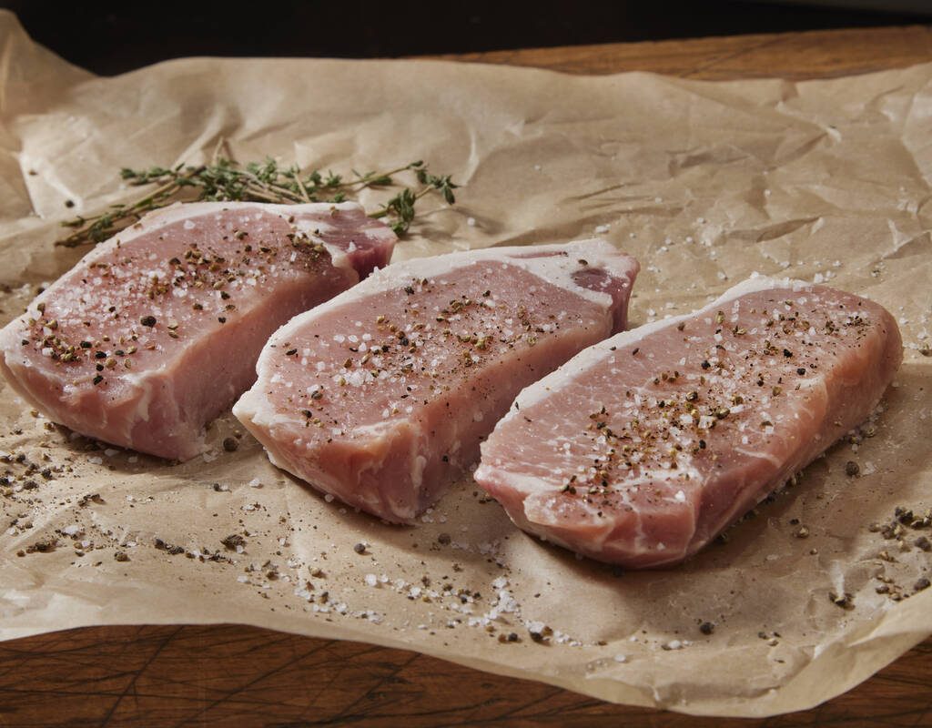 Pork chops sitting on brown paper. Photo: Lauri Patterson/iStock/Getty Images