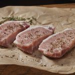 Pork chops sitting on brown paper. Photo: Lauri Patterson/iStock/Getty Images