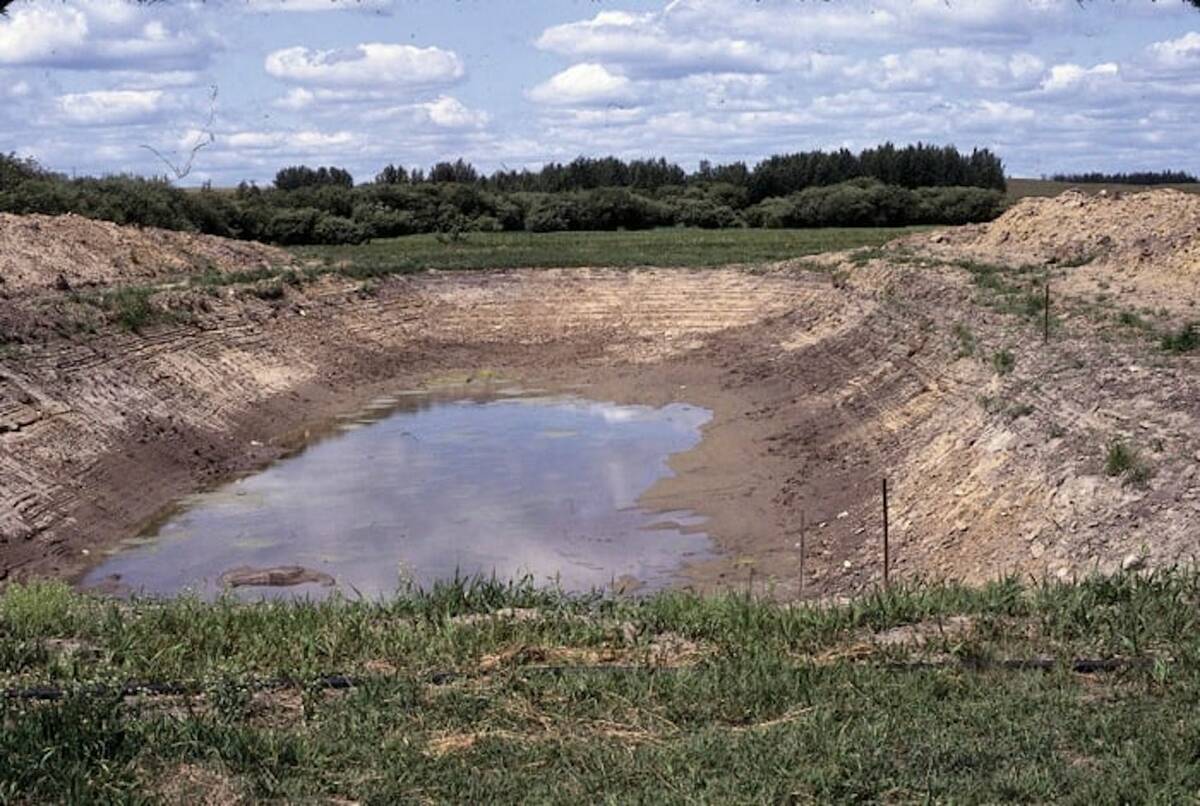 a low-water level dugout on a pasture during drought conditions