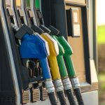 Fuel guns at the fuel station and green field in the background. Photo: Getty Images Plus.