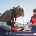 Two salmon farmers inspect a fish. Salmon is in high demand. Photo: Supplied