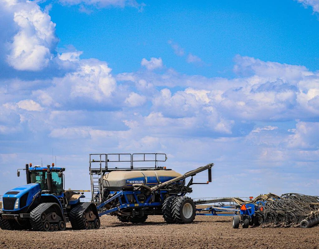 A blue tractor pulling a blue and yellow air seeder setup under a blue sky. Photo: Sonia Third