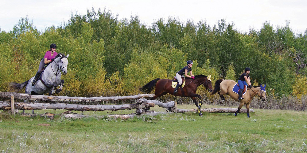 Riders jump an obstacle.